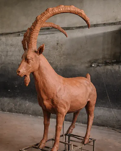 Bronze ibex goat statues with large curved horns standing together